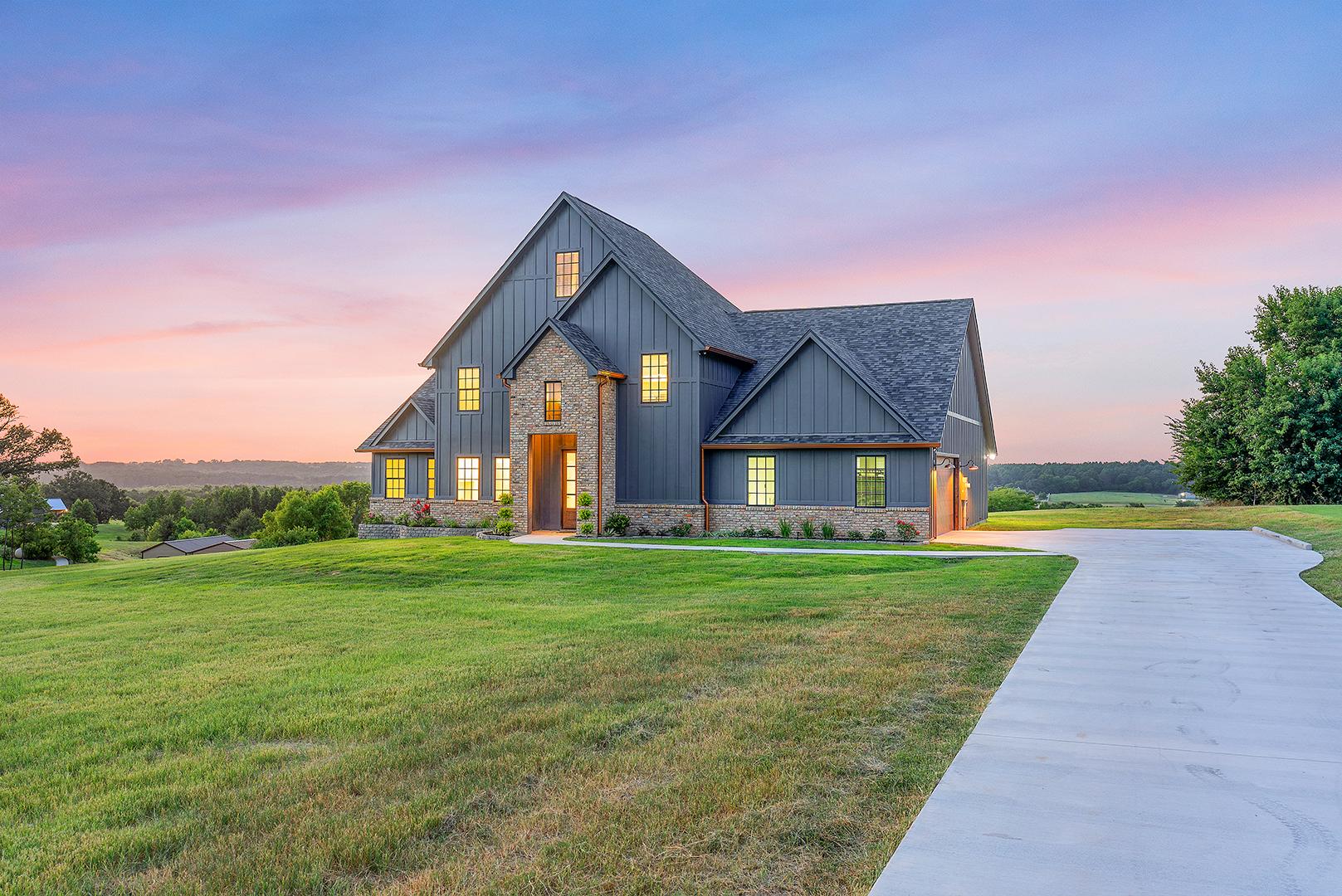 A large house is sitting on top of a lush green field.