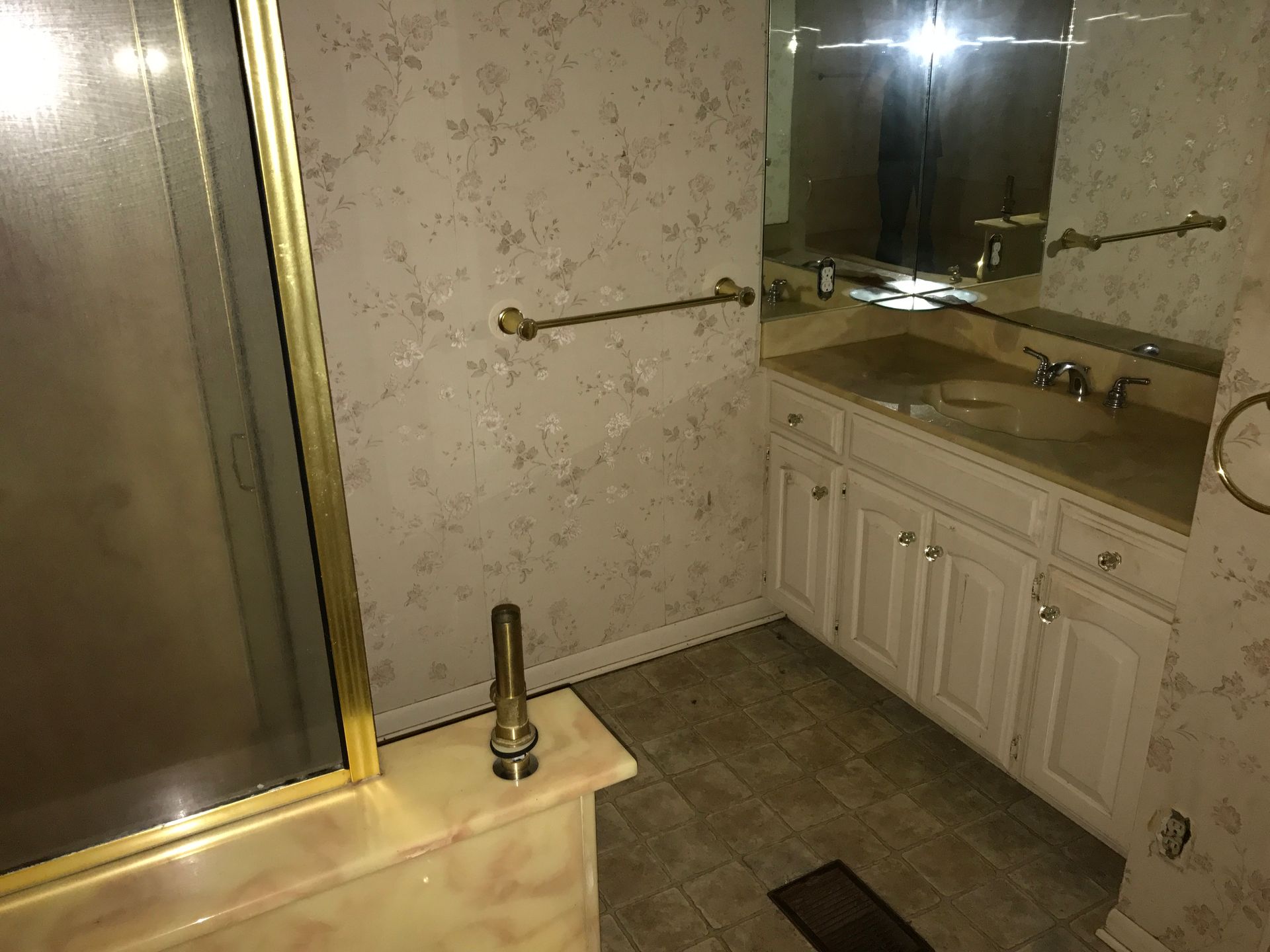 A bathroom with a sink , mirror and shower stall.
