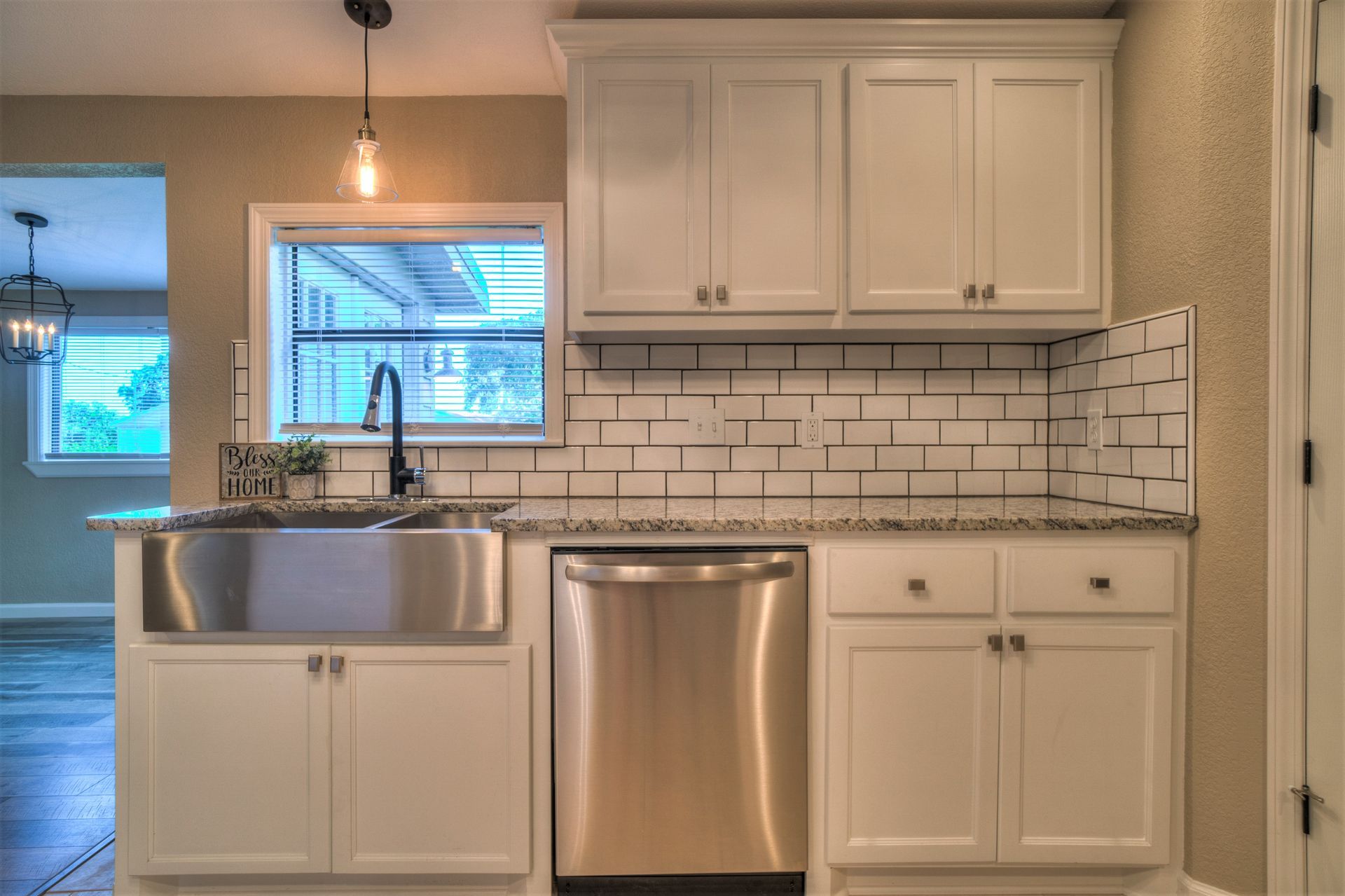 A kitchen with white cabinets , stainless steel appliances , a sink , and a window.
