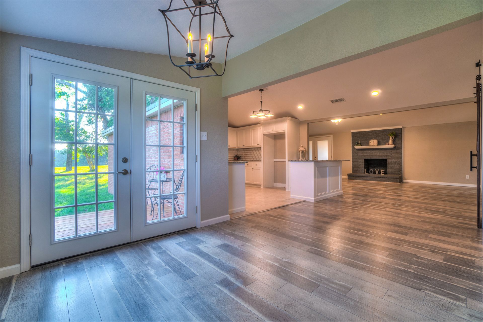 An empty living room with hardwood floors and a chandelier.