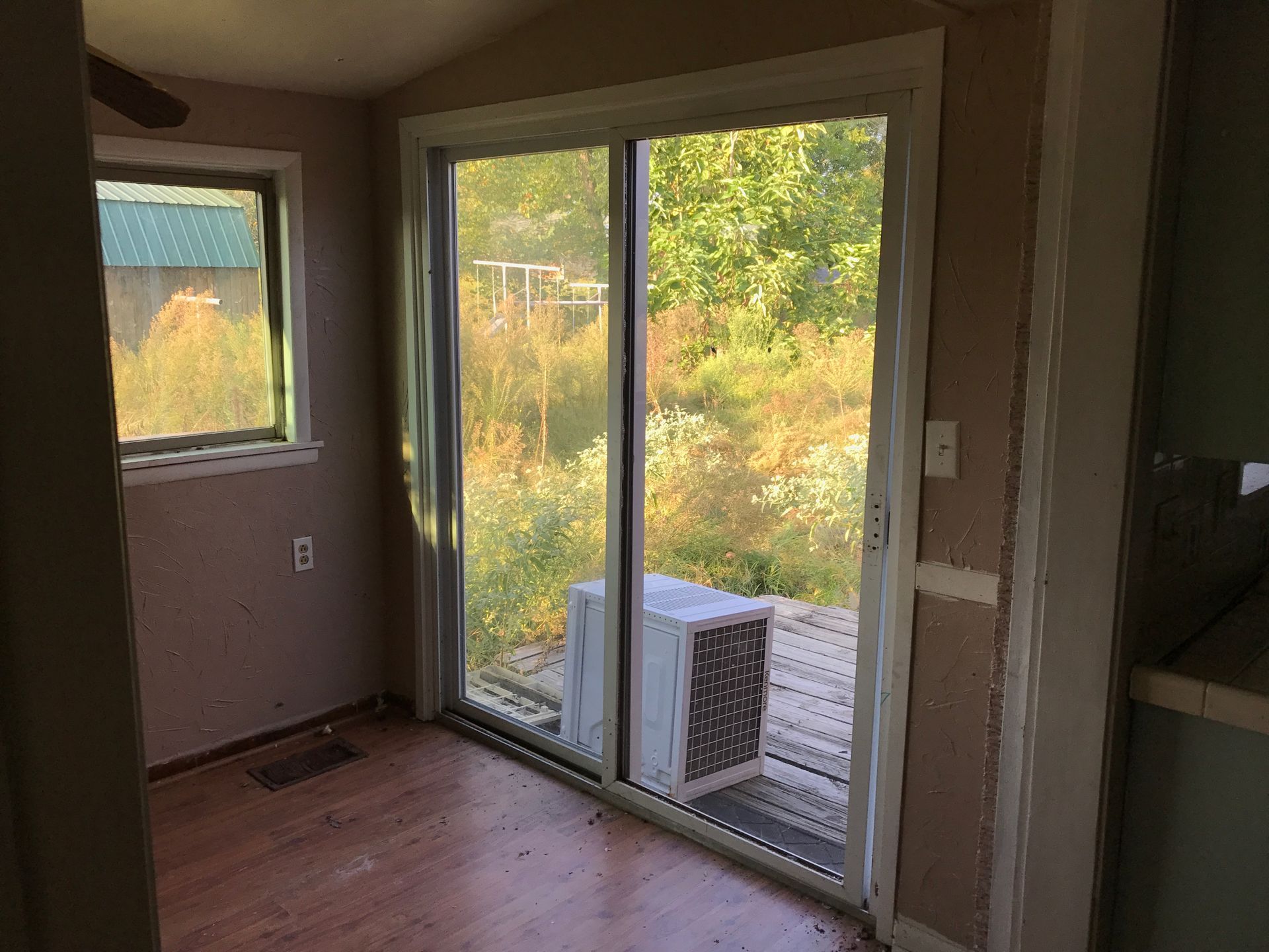 An empty room with a sliding glass door and a window.