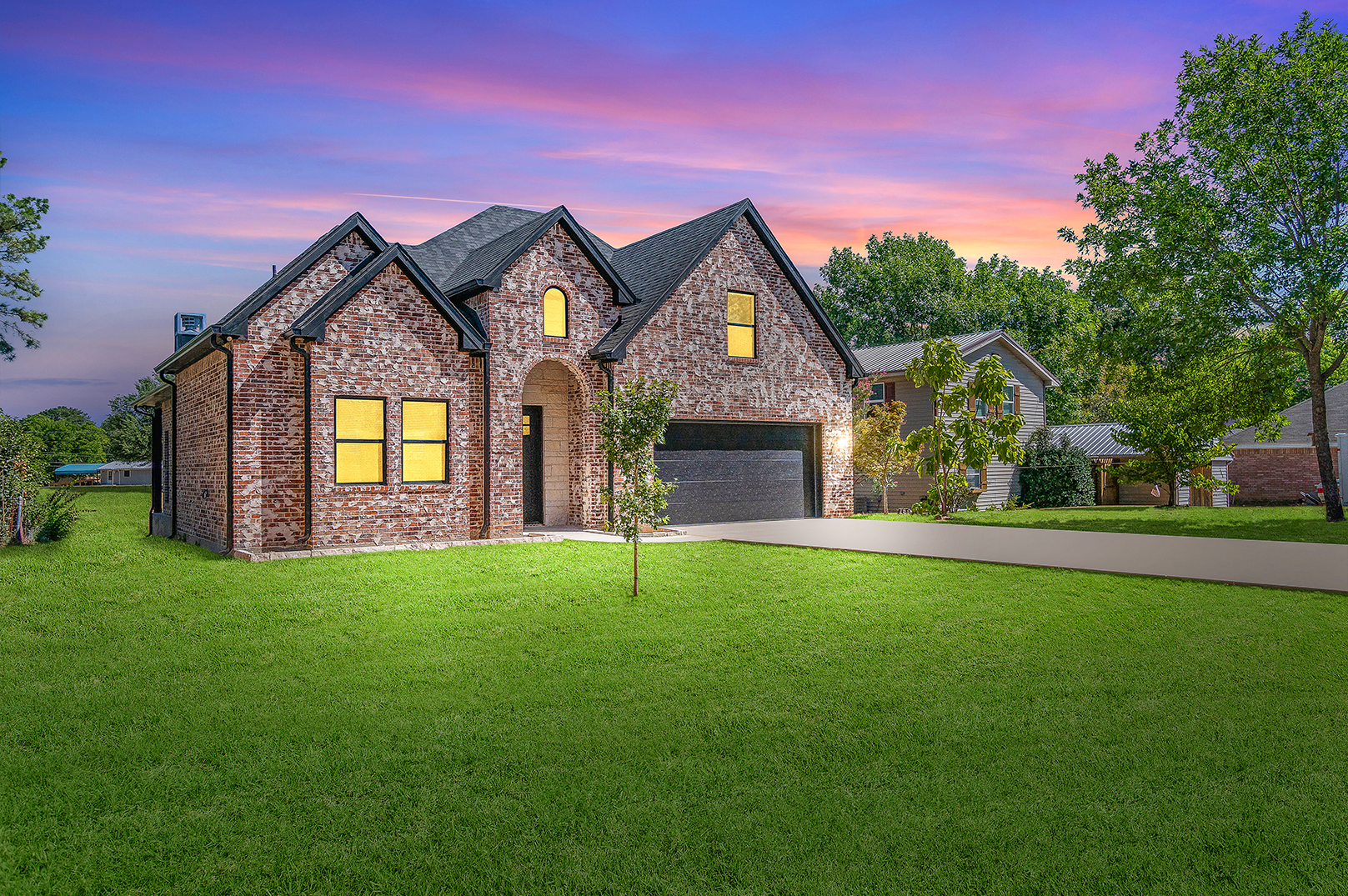 A large brick house is sitting on top of a lush green lawn.