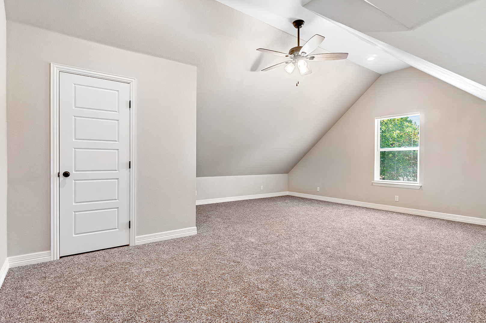 An empty bedroom with a ceiling fan and a window.
