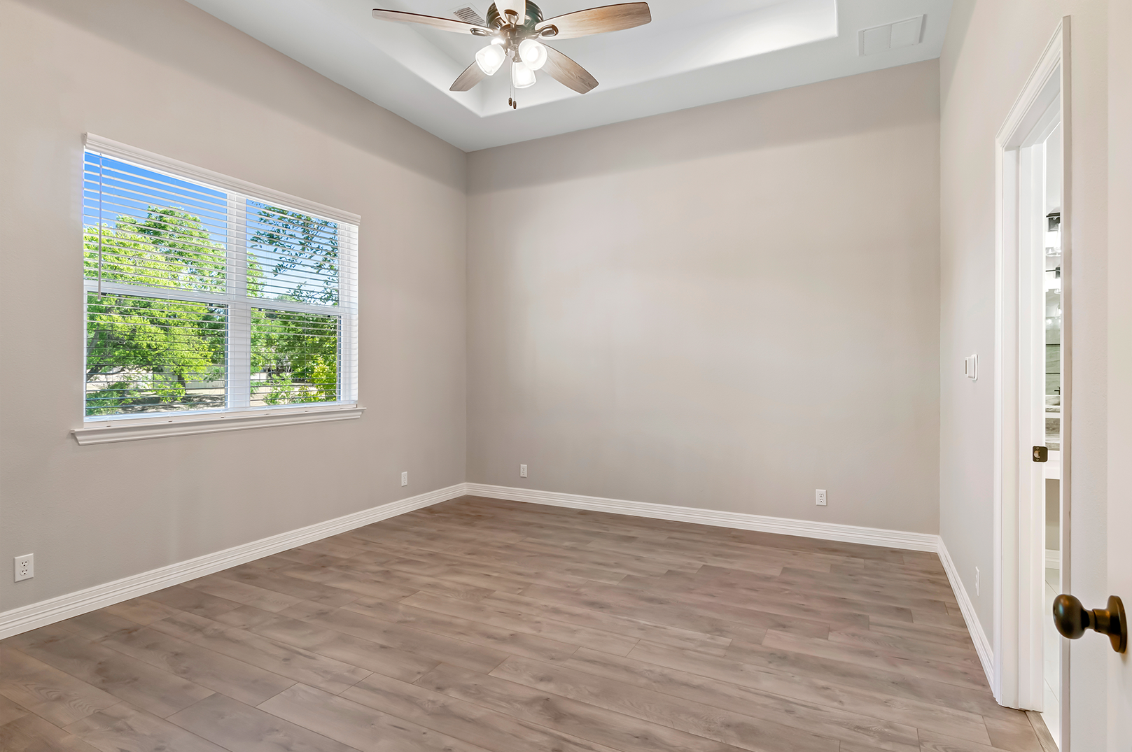 An empty bedroom with hardwood floors and a ceiling fan.
