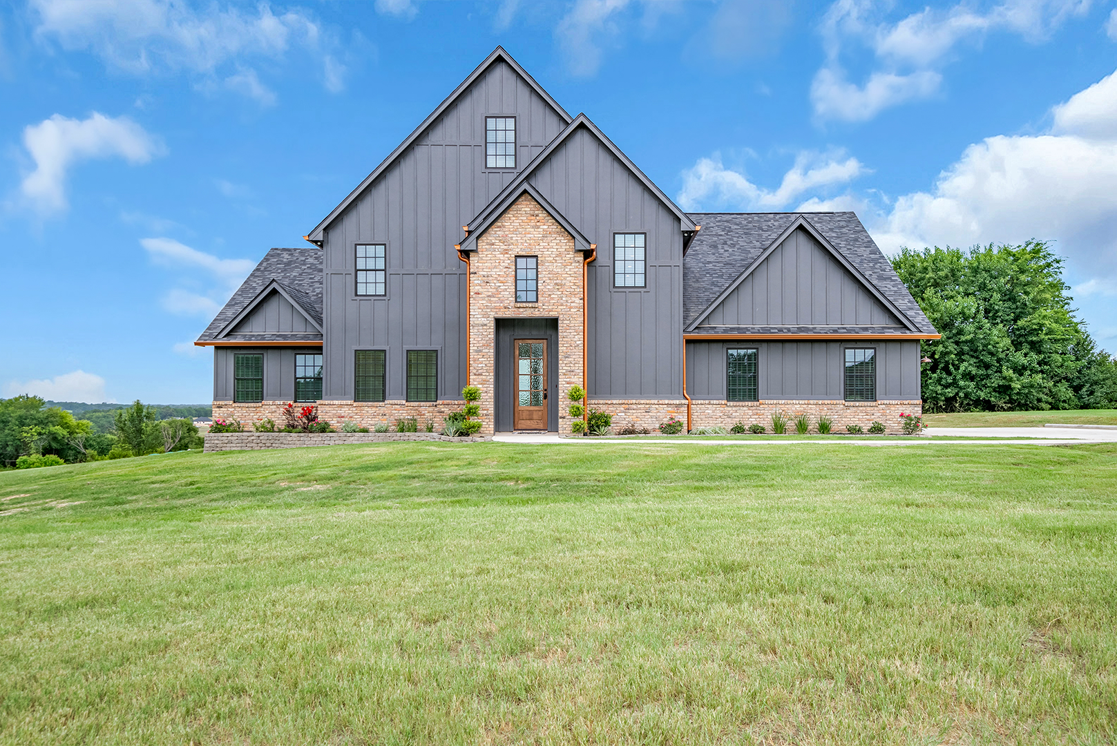 A large house is sitting on top of a lush green field.