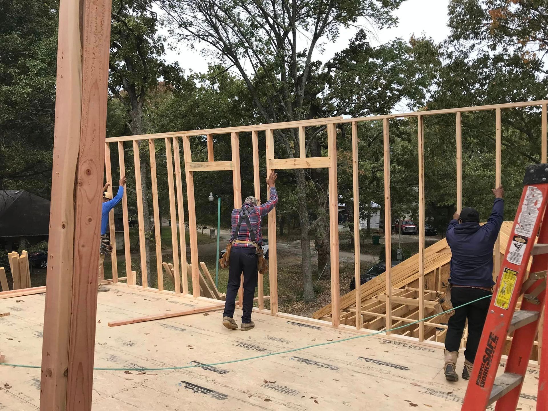 A group of construction workers are working on a wooden wall.