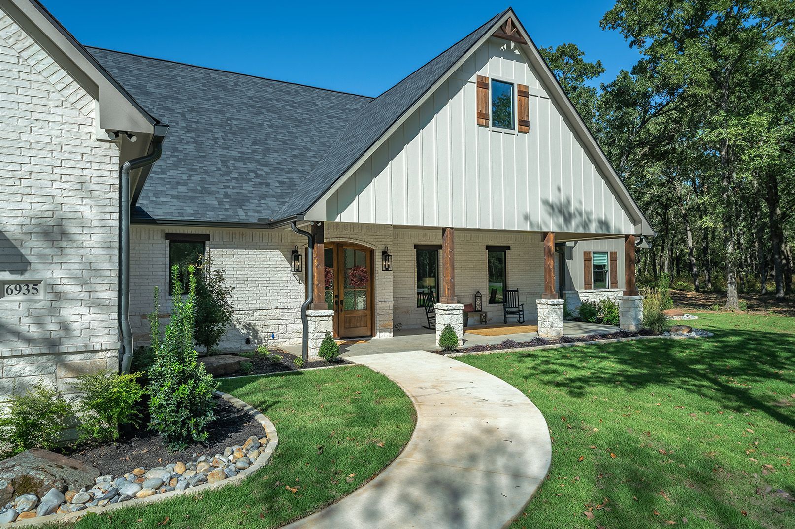 A white brick house with a gray roof and a walkway leading to it.