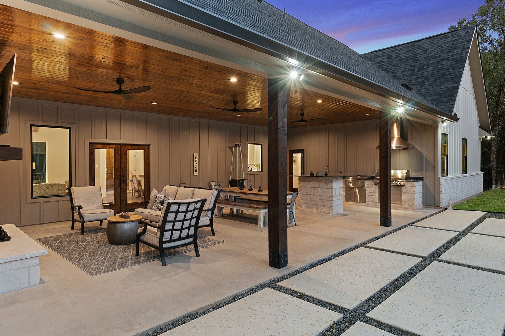 A large covered patio with a lot of furniture and a fireplace.