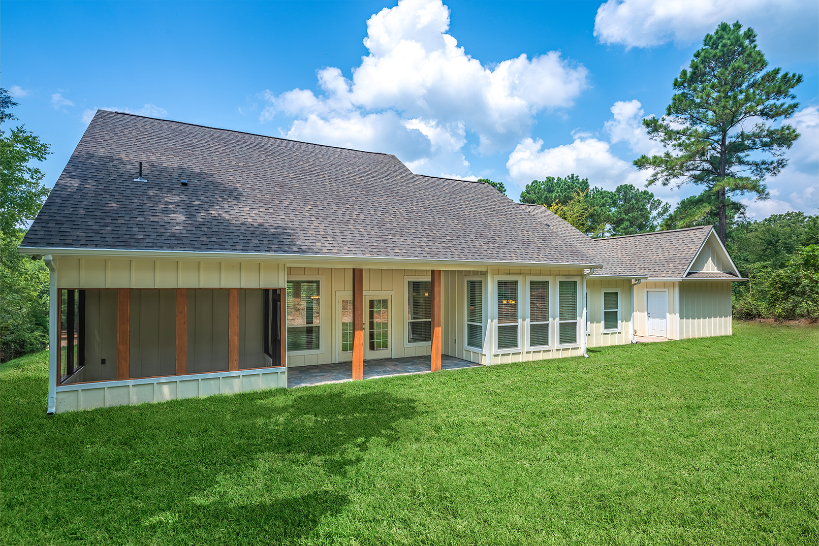 A large house with a gray roof is sitting on top of a lush green field.
