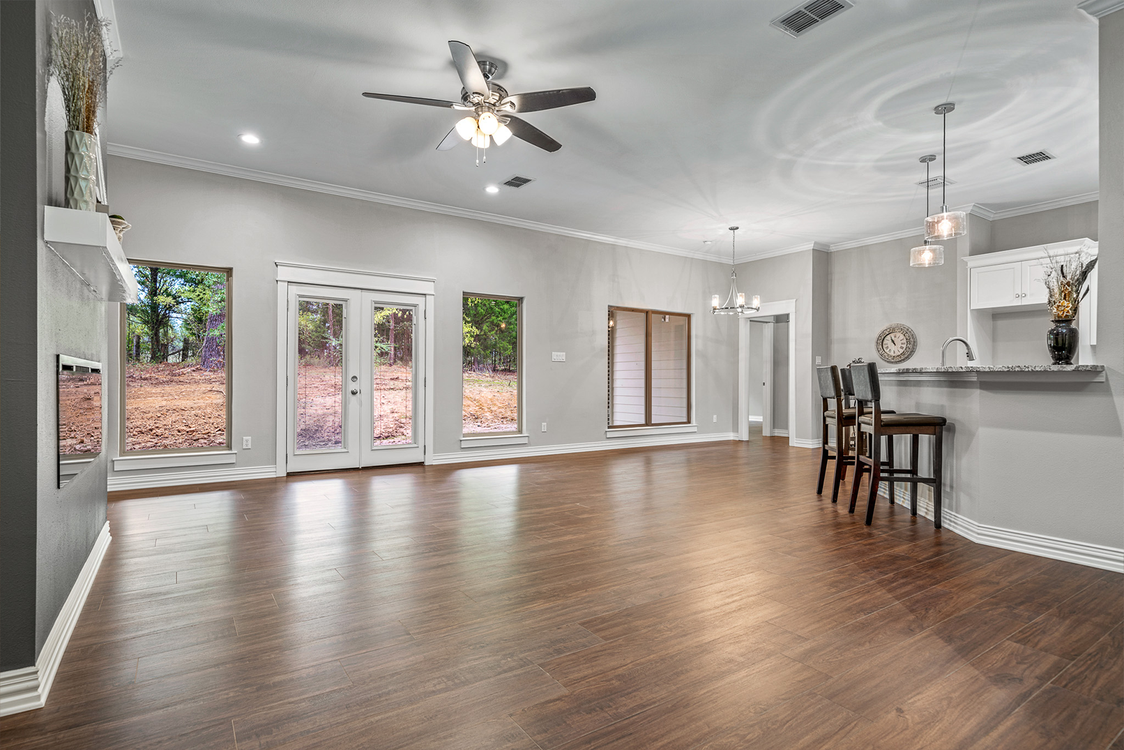 A large empty living room with hardwood floors and a ceiling fan.