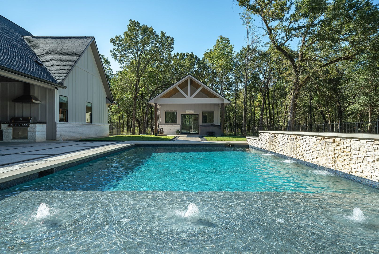 There is a large swimming pool in the backyard of a house.