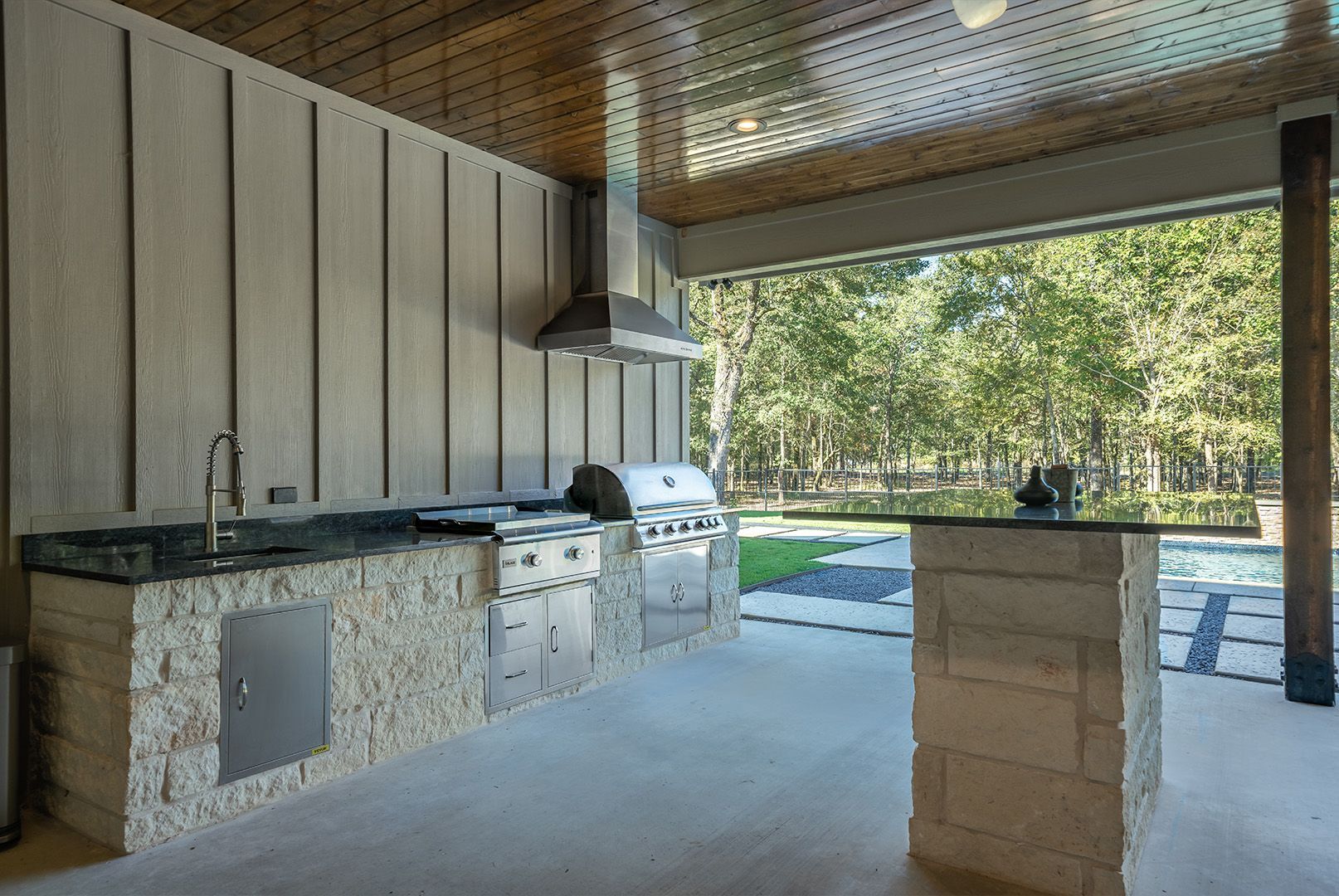 A large outdoor kitchen with a grill and a sink.