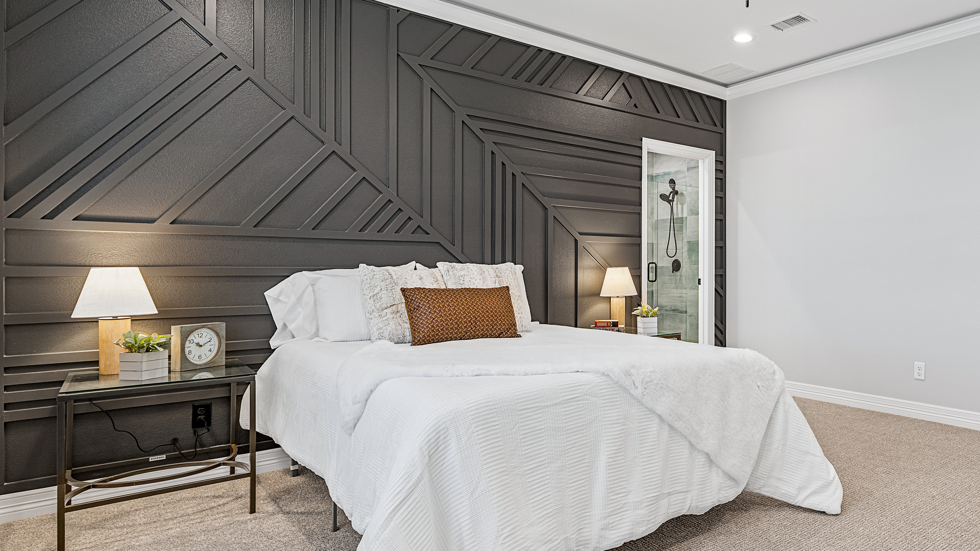 A bedroom with a bed , nightstands , lamps and a black wall.