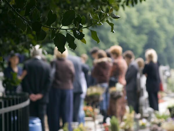 People gathered outdoors during a memorial service, representing funeral and cremation services in a peaceful setting