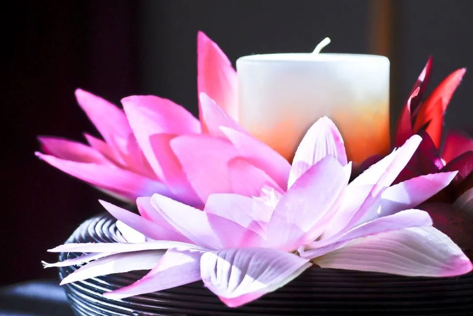 Lit candle nestled among pink lotus-style blooms for a custom memorial, Indianapolis, IN funeral homes