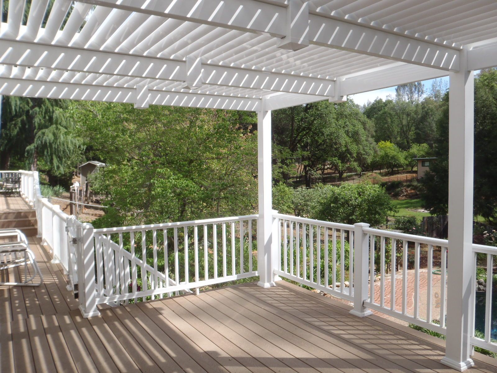 A deck with a white railing and a pergola over it