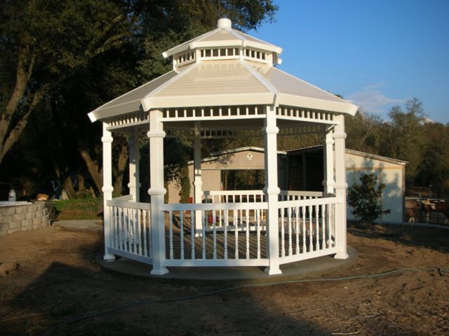 A white gazebo is sitting in the middle of a dirt field