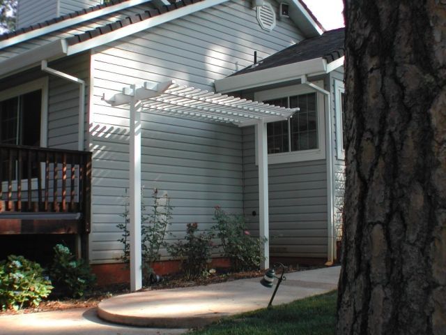 A house with a white pergola on the side of it