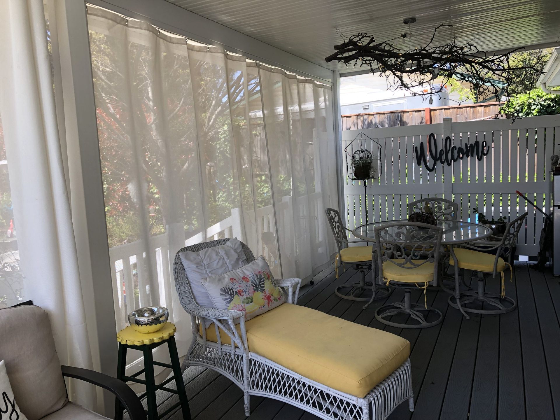 A porch with a wicker chair , table and chairs.