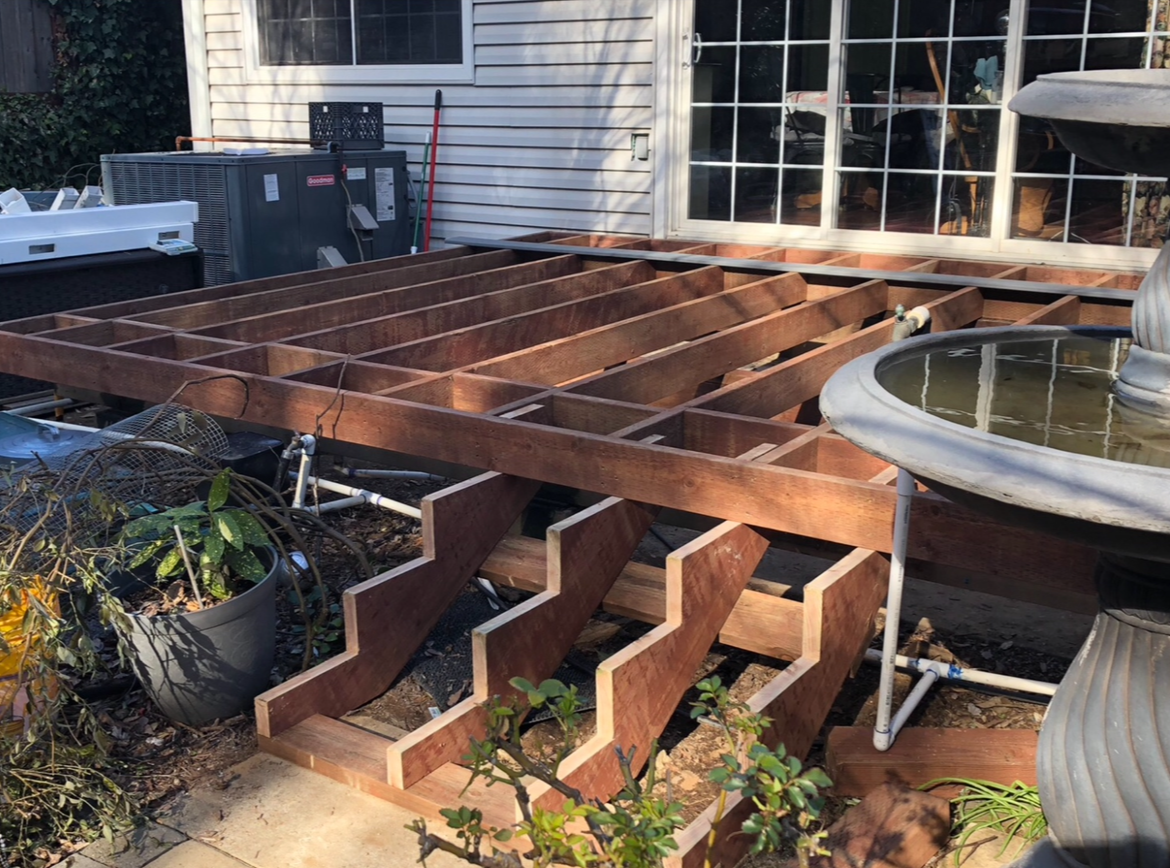 A deck with a white railing and a pergola over it