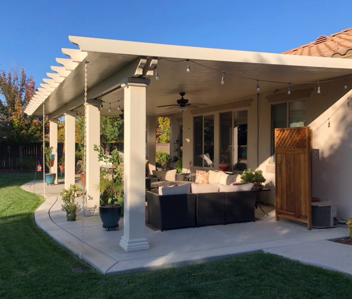 There is a patio with a table and chairs under a pergola.