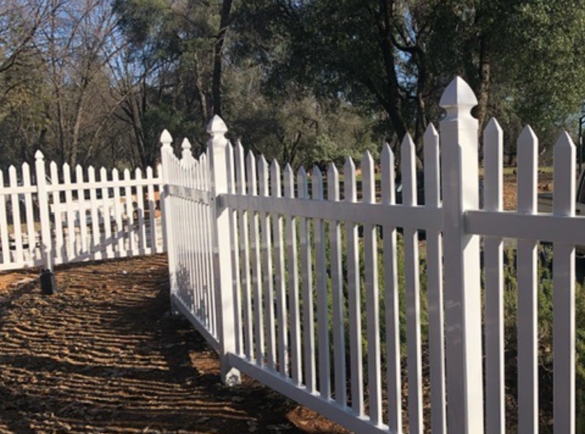 A white picket fence surrounds a lush green field.