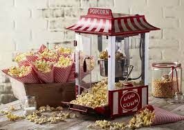 Popcornmachine met een rood-wit gestreept afdak en popcornhoorntjes gevuld met verse popcorn.