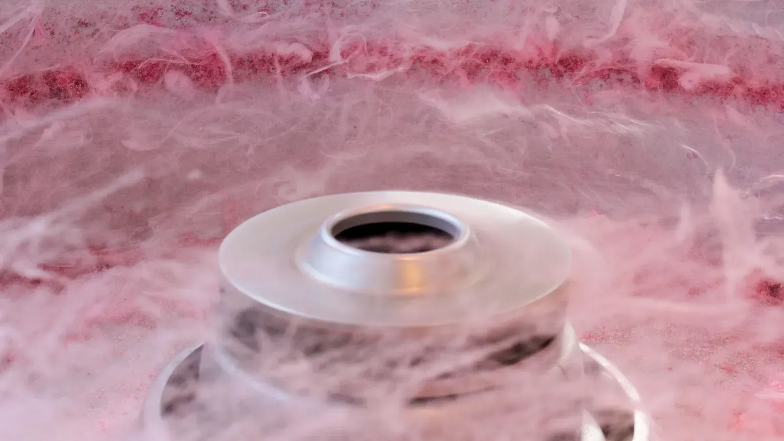 Een suikerspinmachine draait roze suiker rond en creëert zo een pluizige wolk.