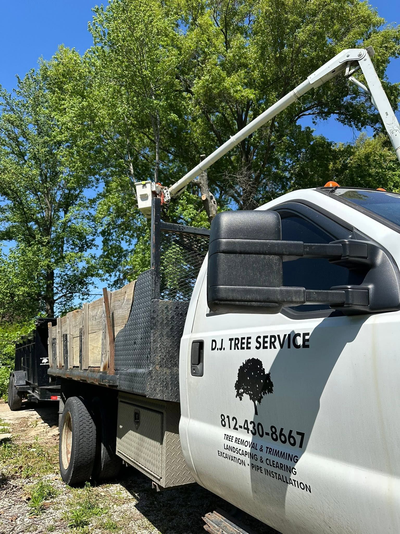 White work truck with J&J Tree Service logo parked by trees on a sunny day