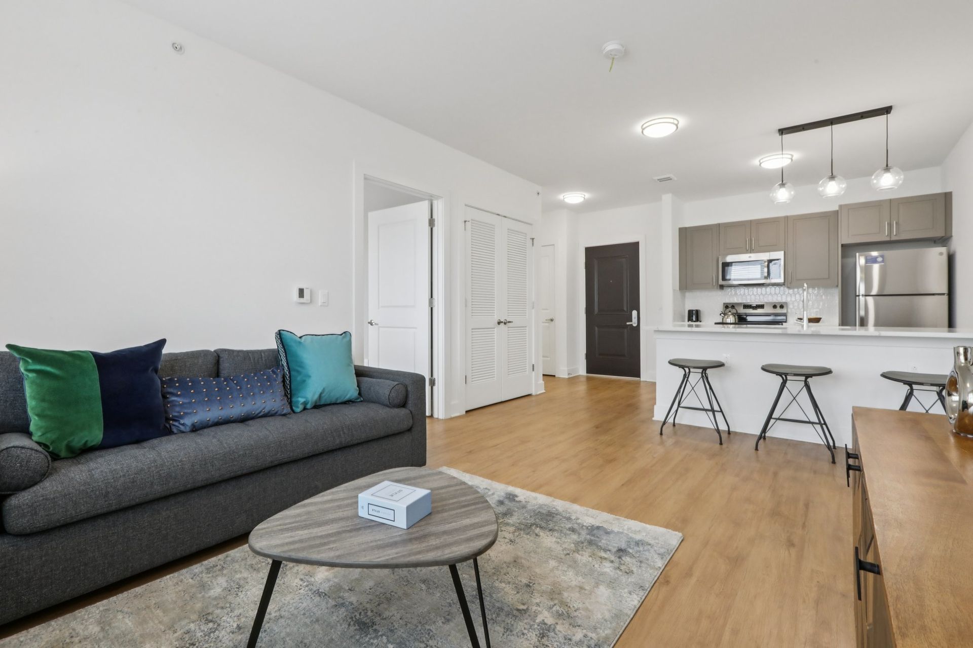 Open living room and kitchen with green throw pillows at Meridia Little Ferry, Little Ferry NJ