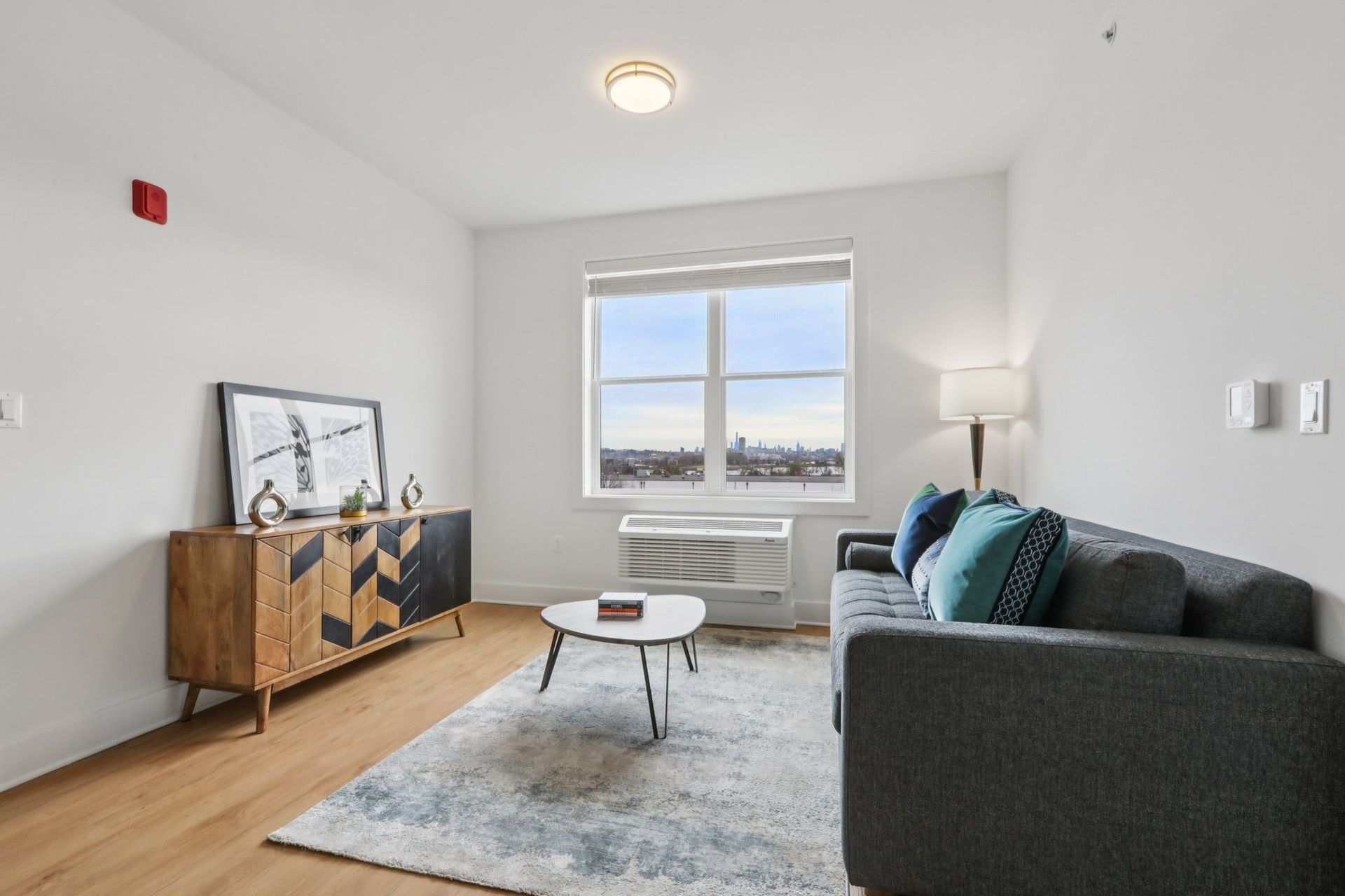 Sunny living room with sofa and hardwood floors at Meridia Little Ferry apartments NJ