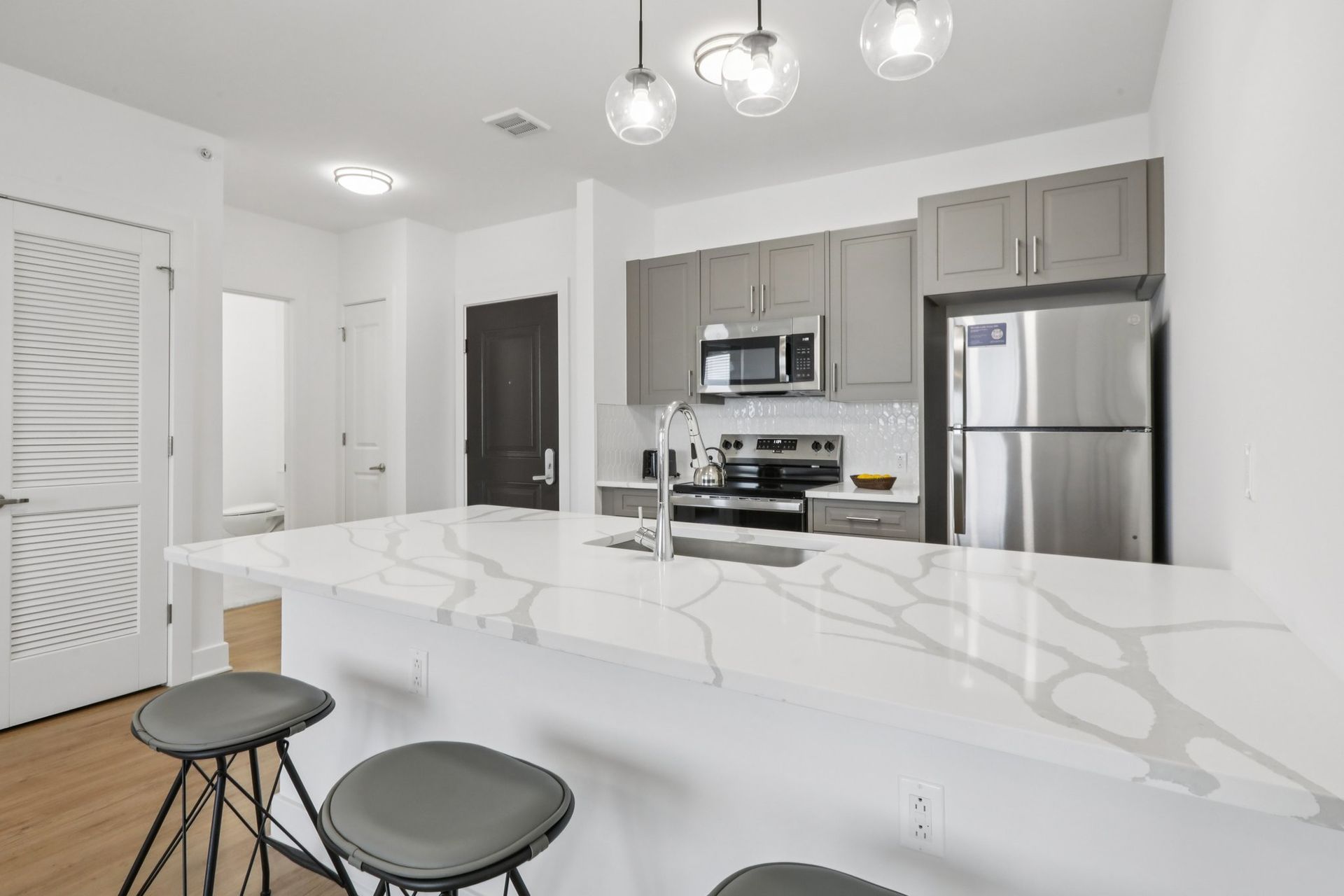 White marble kitchen island with stainless refrigerator at Meridia Little Ferry apartments NJ