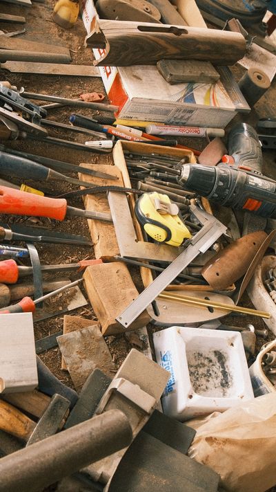 Assorted hand tools scattered on a workbench, including a saw, hammer, and screwdrivers.