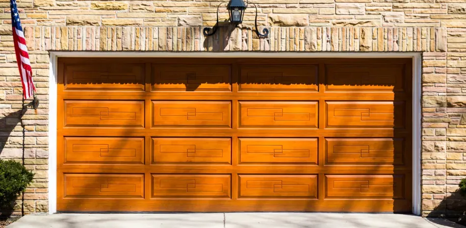 A wooden garage door is sitting in front of a brick building.