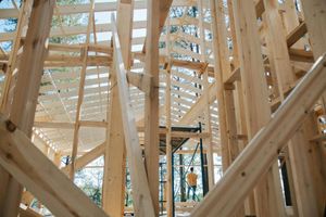 A man is standing in the middle of a wooden structure under construction.