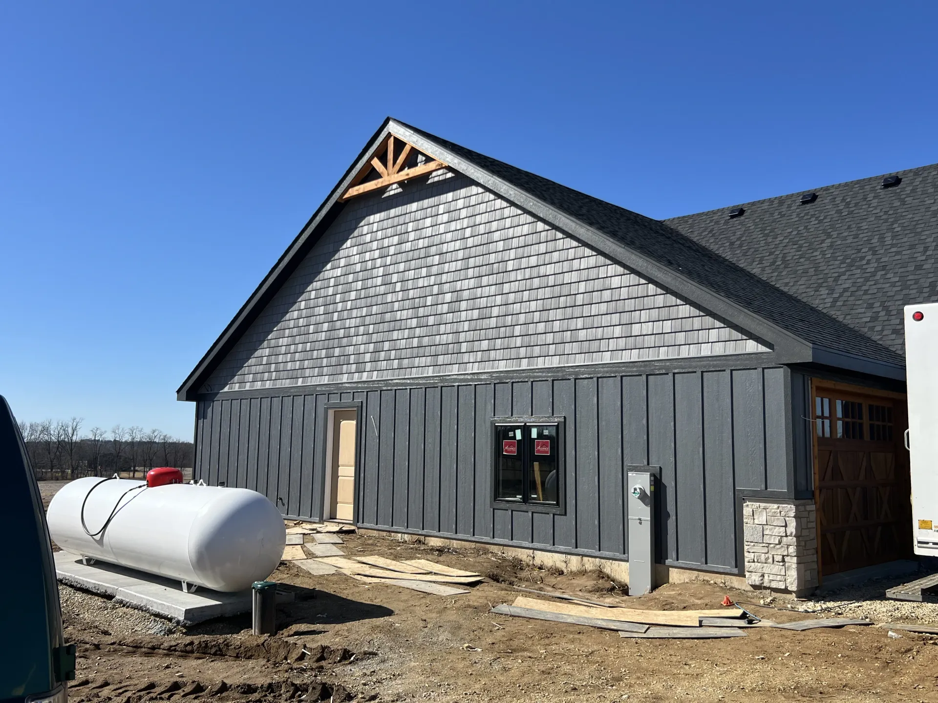 New gray building under construction with a white propane tank beside it