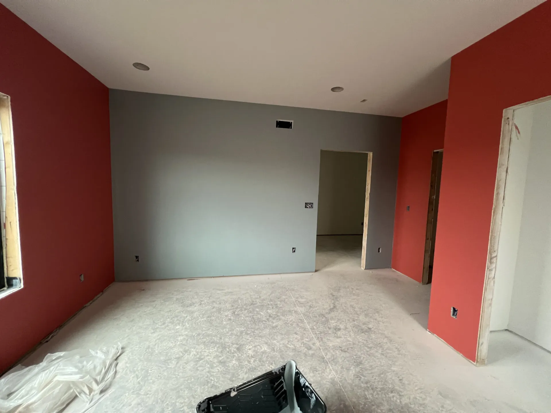 Empty unfinished room with red and gray walls, white floor, and doorway openings.