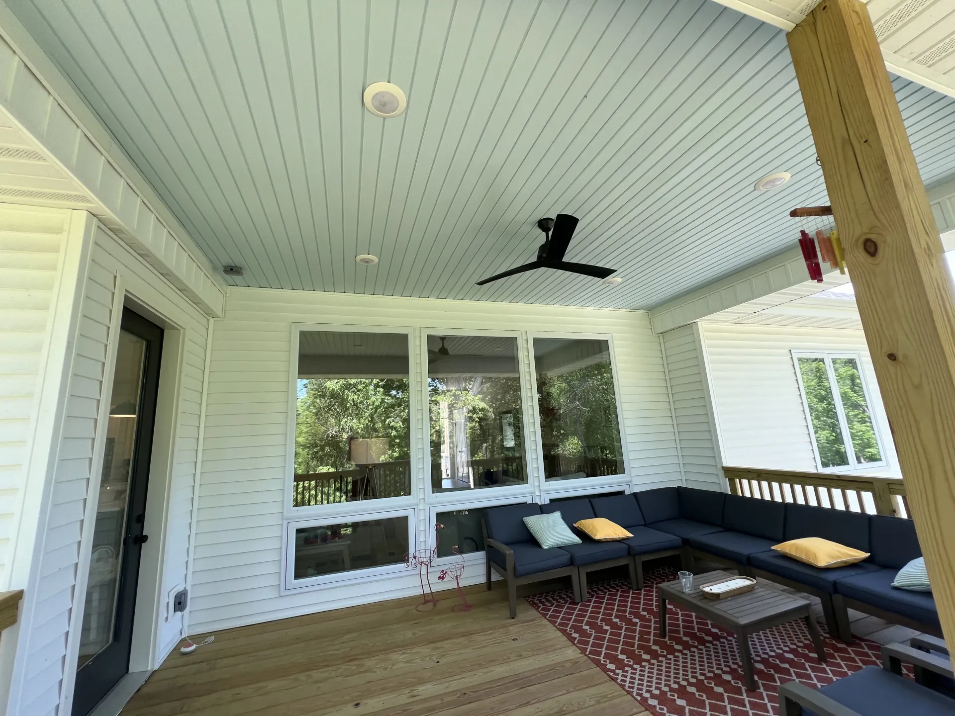 Covered porch with white ceiling, ceiling fan, sectional sofa, and glass sliding doors