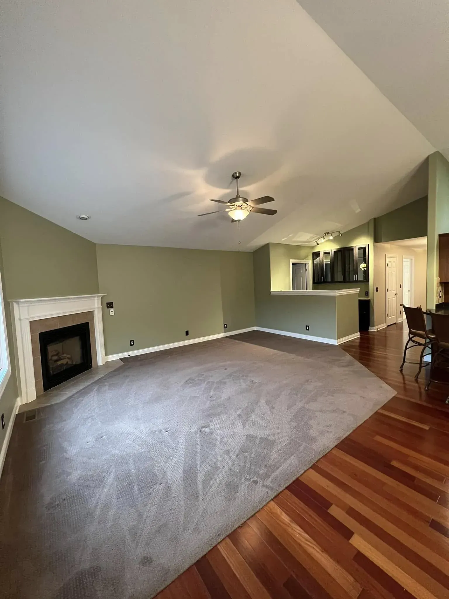 Interior painting project with green living room walls, white trim, fireplace, and hardwood floors near Sterling IL