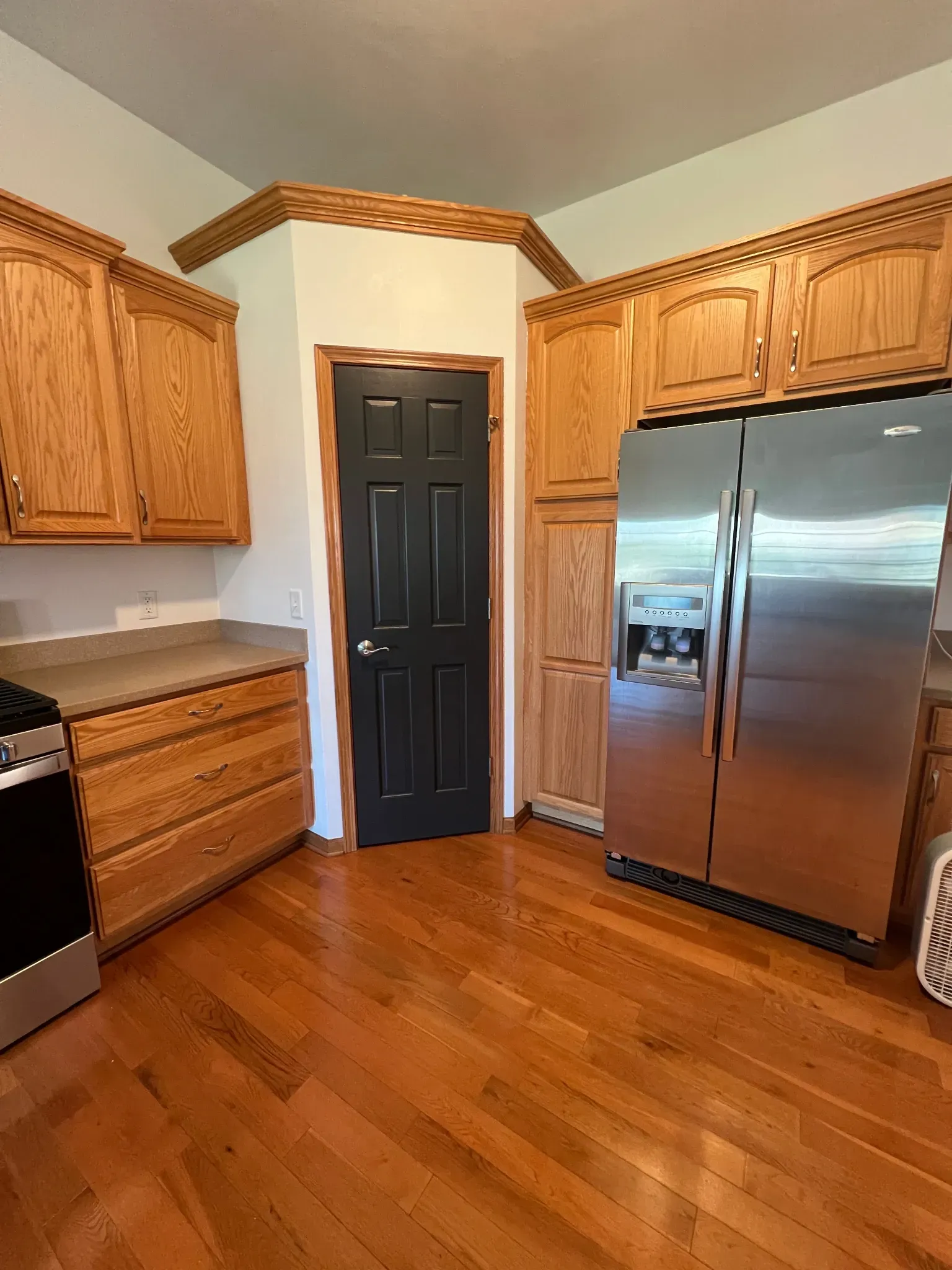 Residential interior painting project with black painted pantry door, wood trim, and kitchen cabinets near Dixon IL