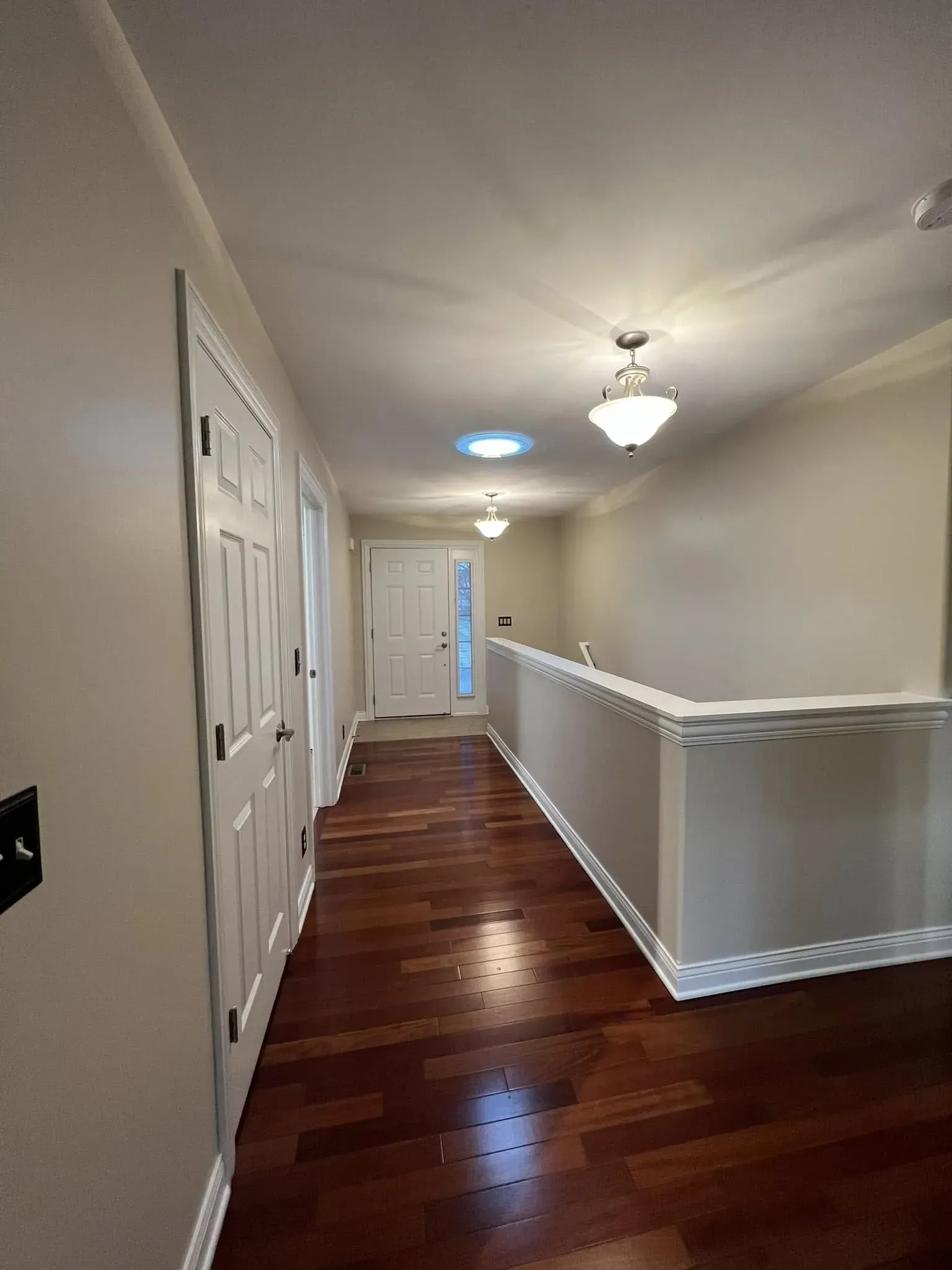 Interior painting project with updated neutral hallway walls, white trim, and wood flooring near Dixon IL