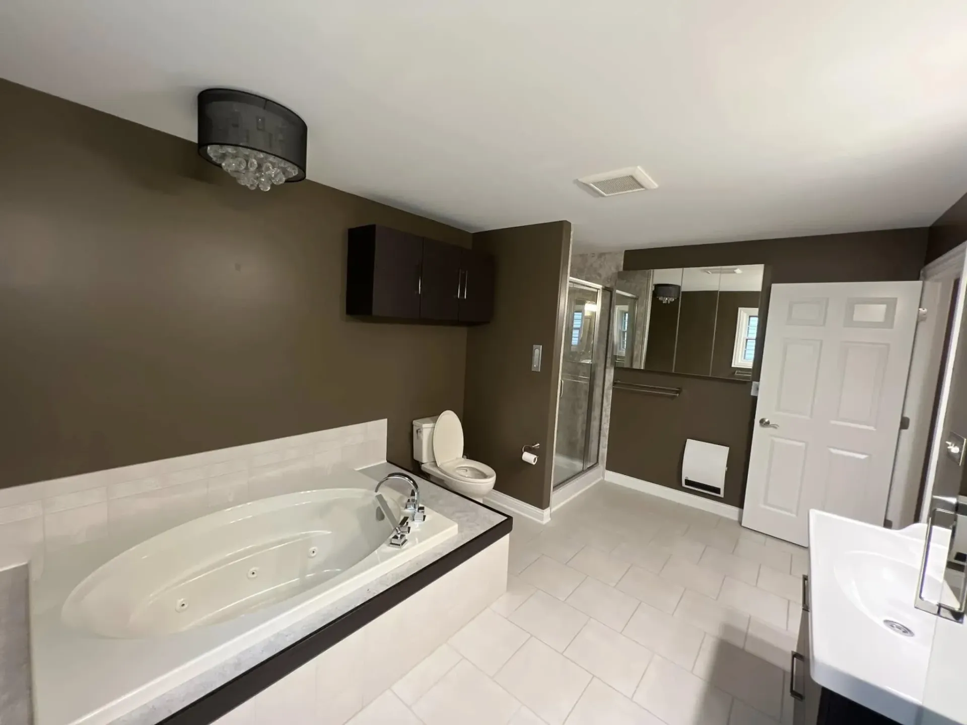 Bathroom with white tub, dark walls, mirror, vanity, and tiled floor