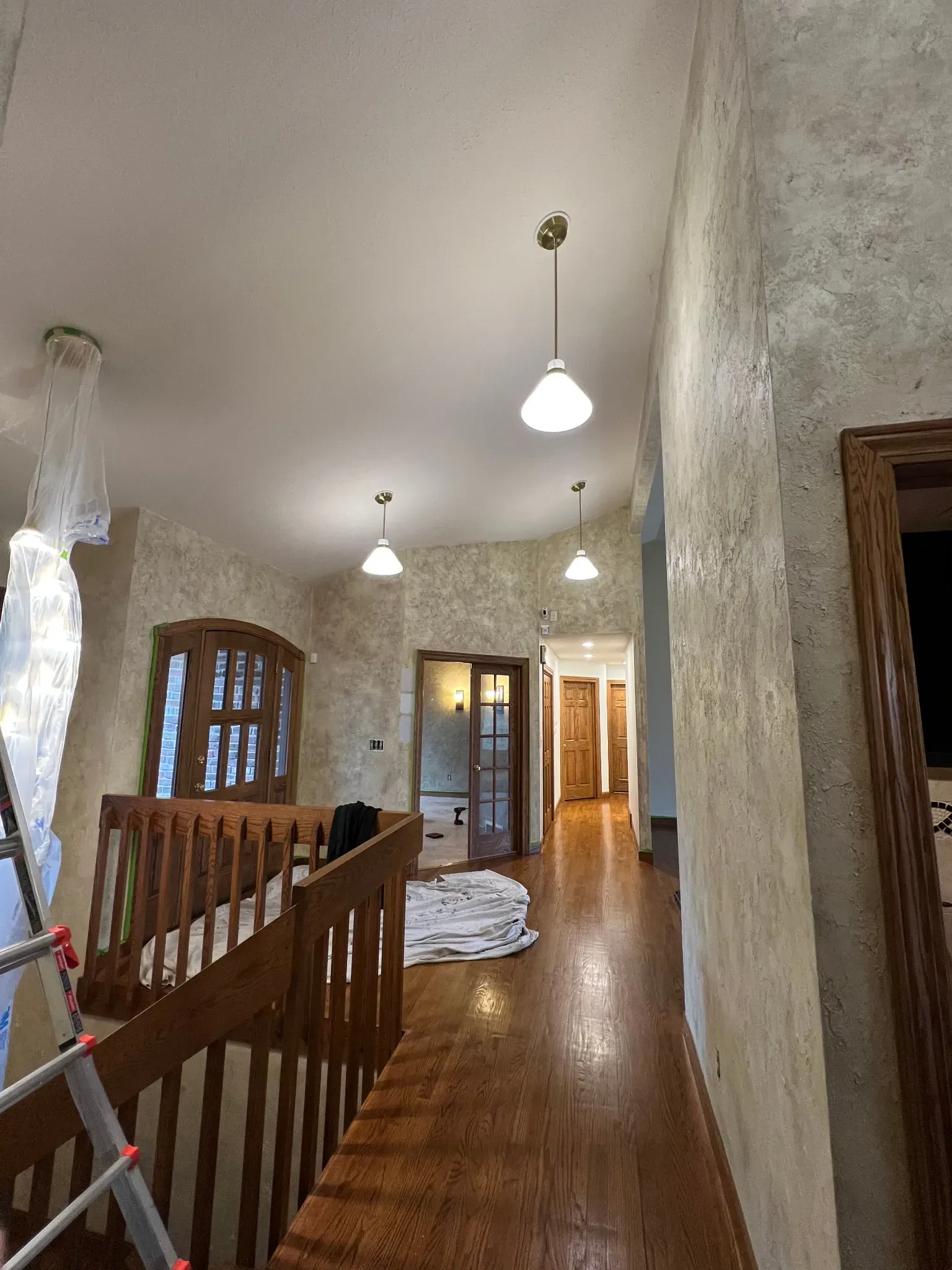 Residential interior painting project with textured foyer walls, hardwood floors, wood trim, and protected work areas near Byron IL