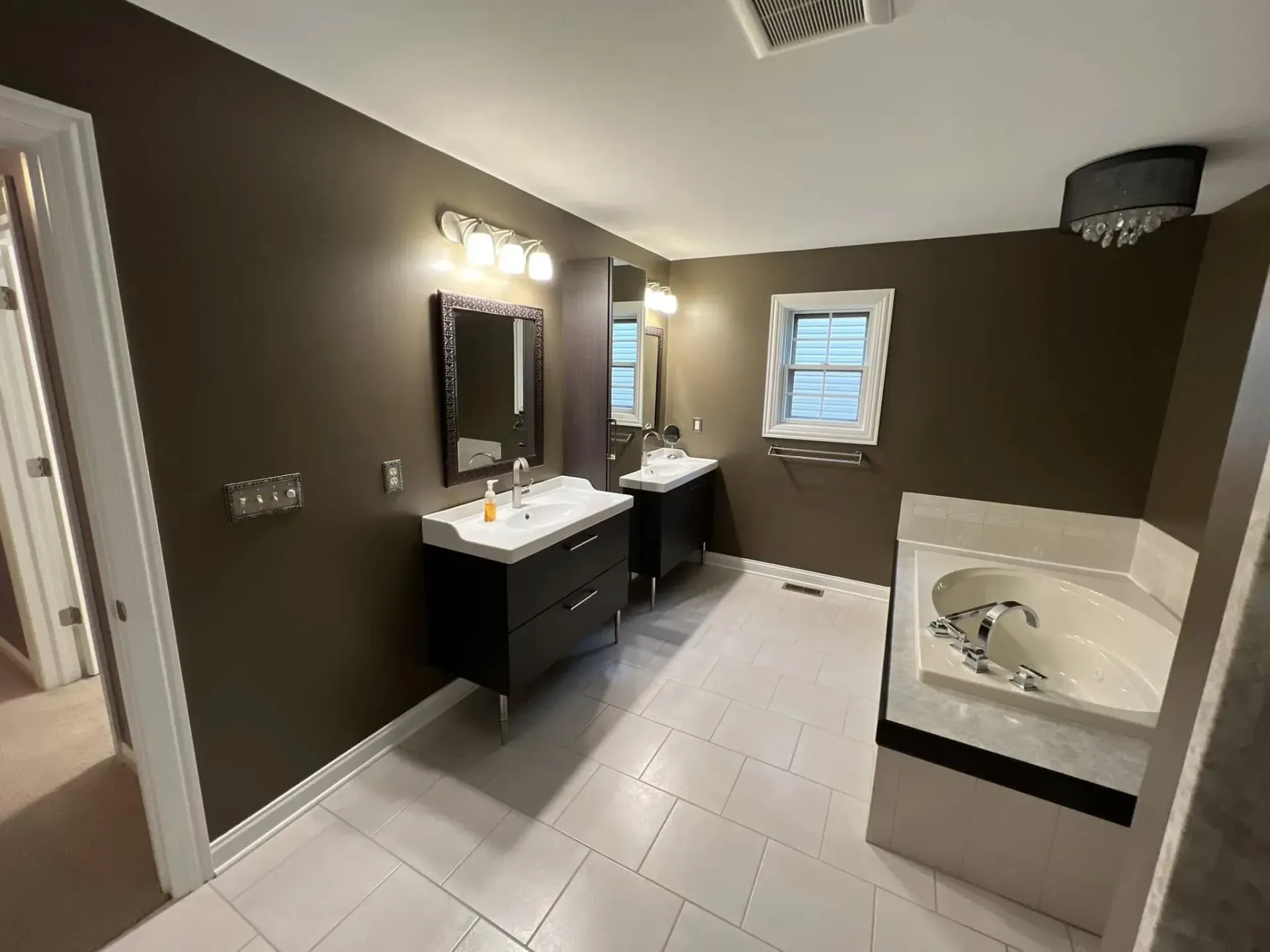 Bathroom interior painting project with brown walls, white trim, double vanities, tile floor, and soaking tub near Byron IL