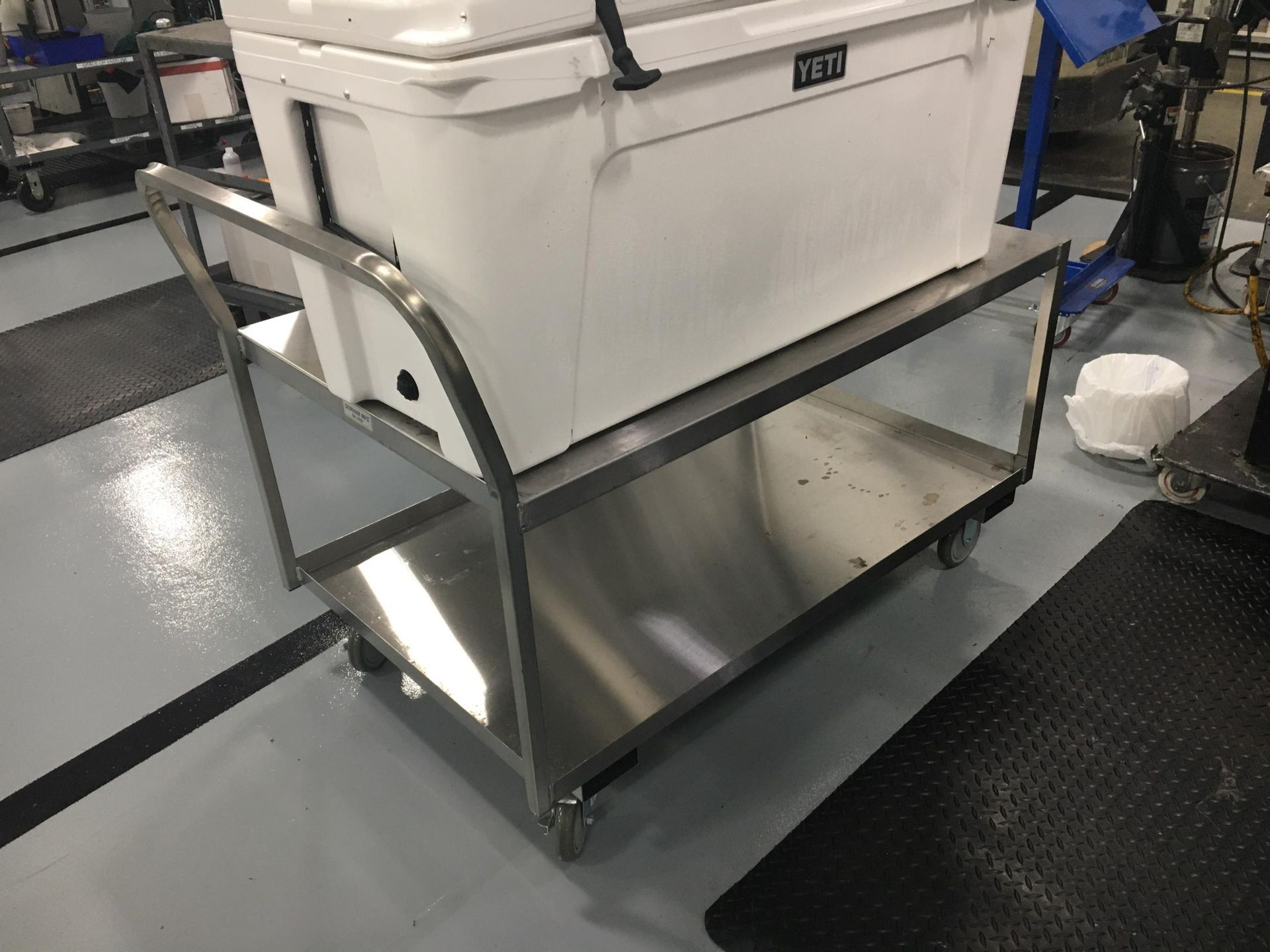 Stainless steel utility cart with a large white cooler on top.