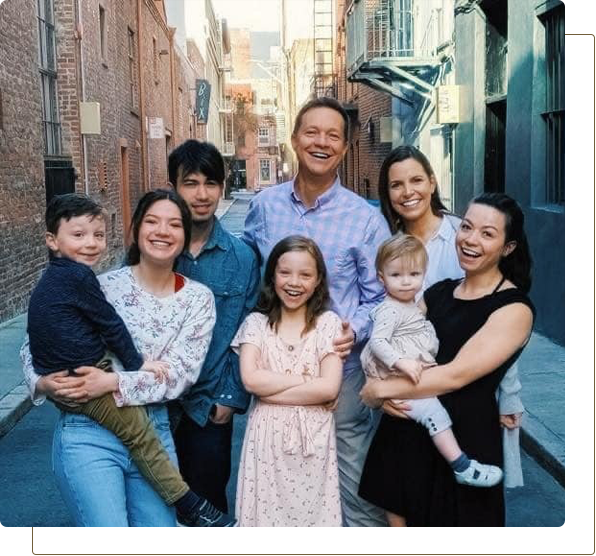 Family group smiling in an alley, with adults and children posing closely together.