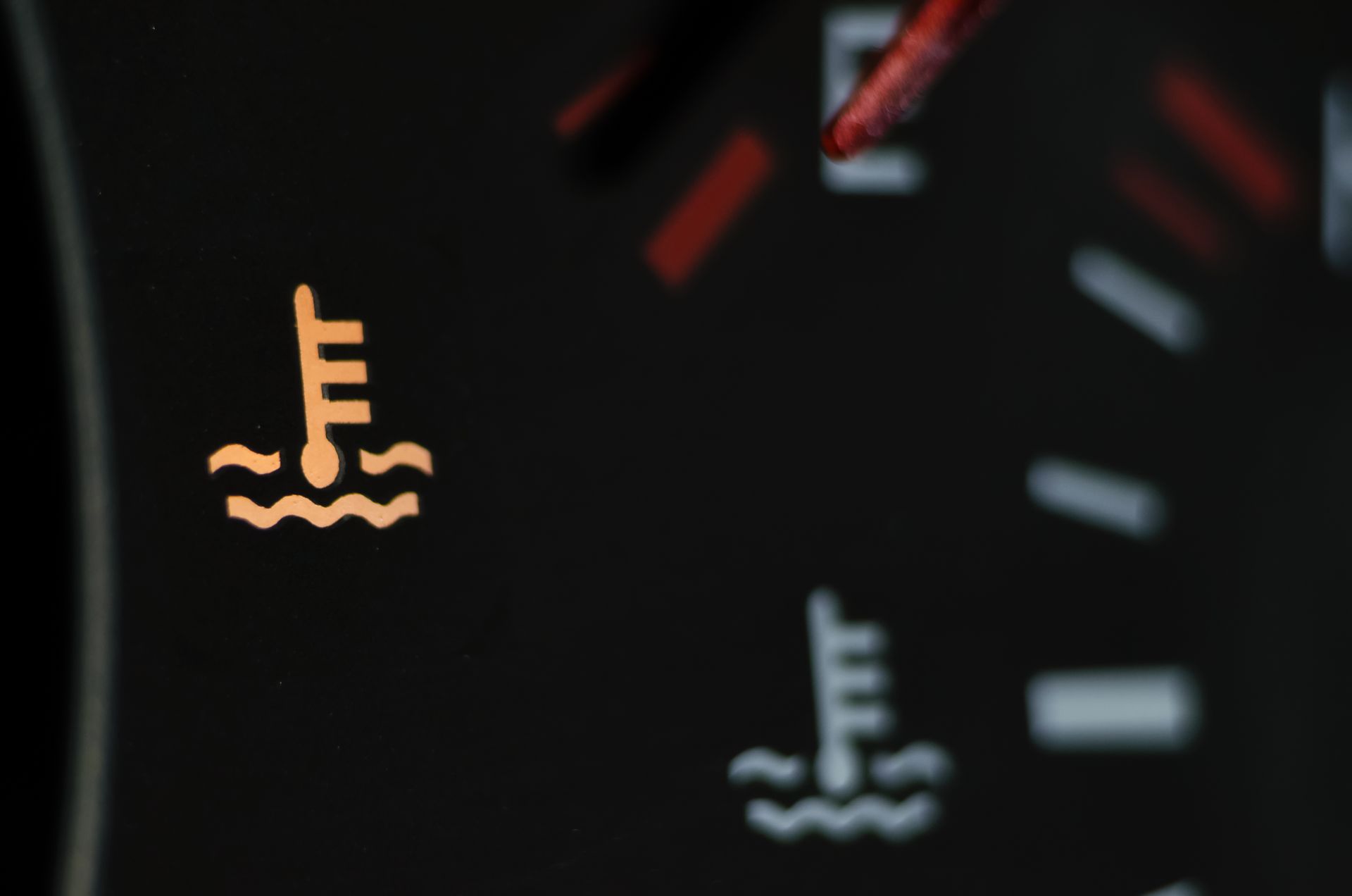 Dashboard warning lights for engine temperature, with one orange and one white icon on a dark car panel | Ron's Auto & RV