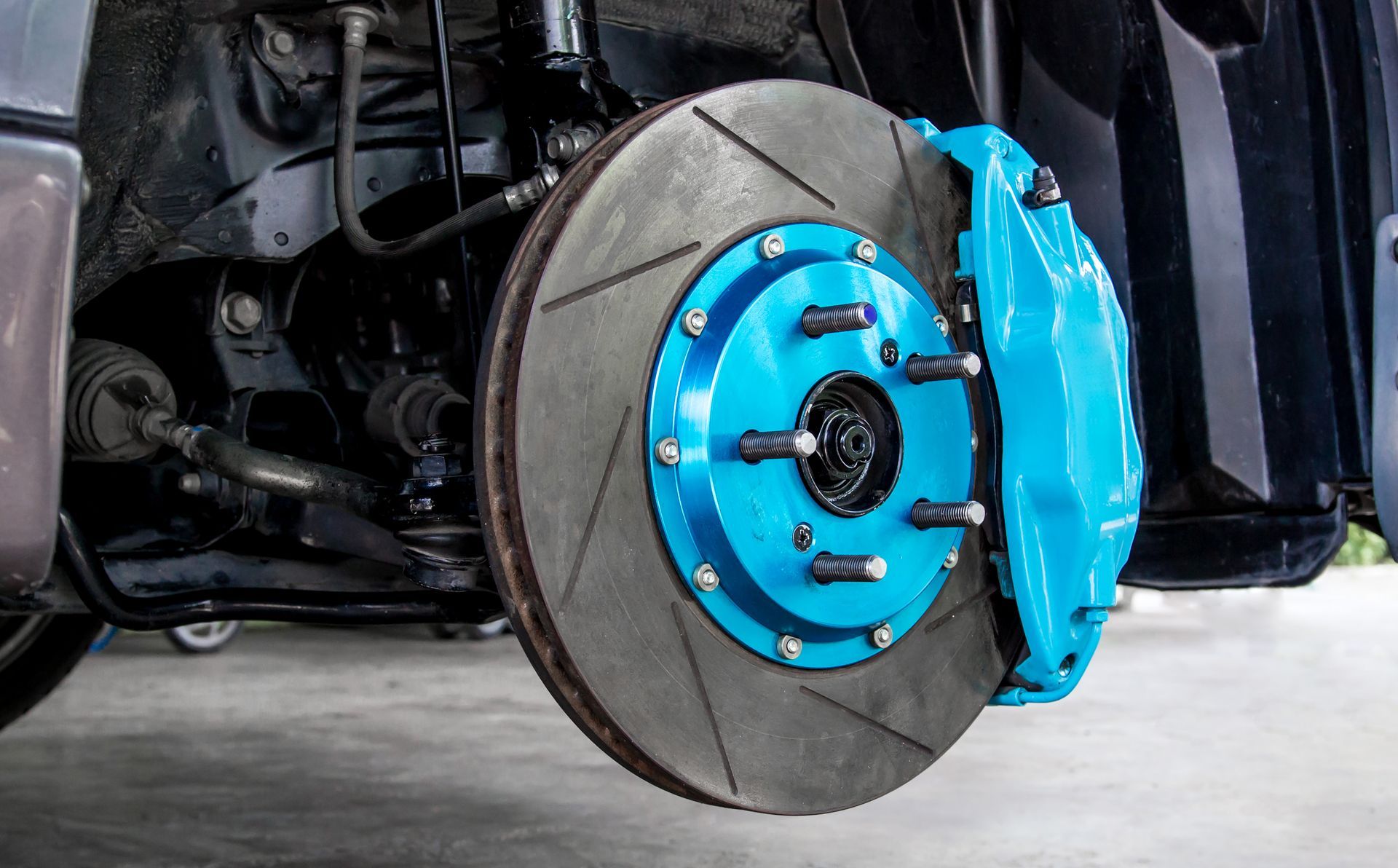 Car with front wheel removed, showing a blue brake rotor and caliper assembly. | Ron's Auto & RV