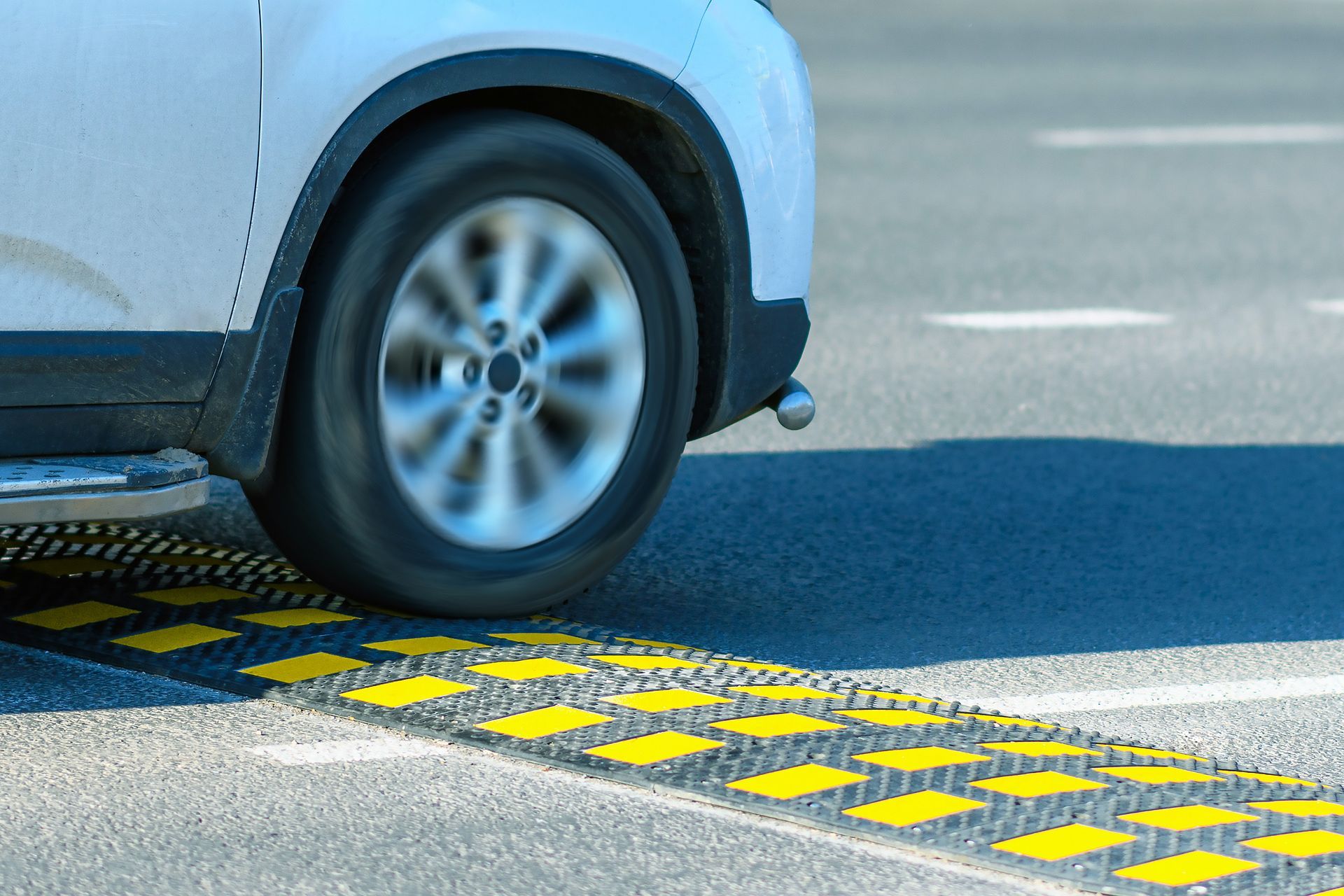 Car wheel crossing a yellow-and-black speed bump on a road | Ron's Auto & RV