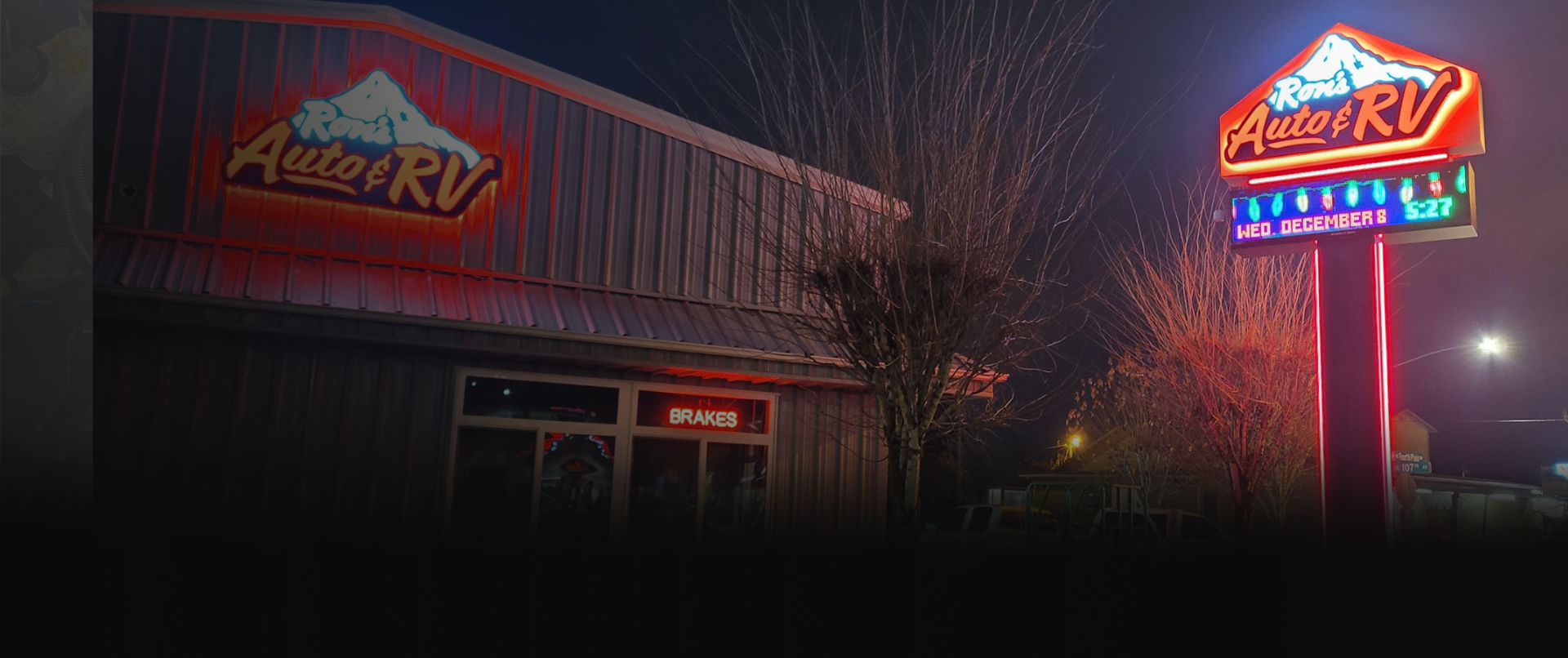 Neon-lit roadside diner at night with a glowing sign and a building reflected in the windows | Ron's Auto & RV